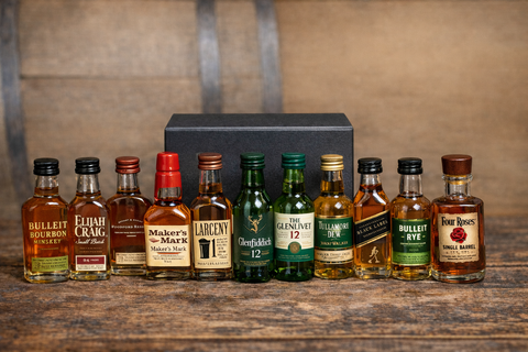 Whiskey sampler set with a variety of bottles in a sleek black gift box on a wooden background.